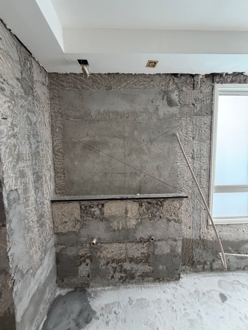 Master bathroom stripped to bare concrete with the unit position marked on the wall